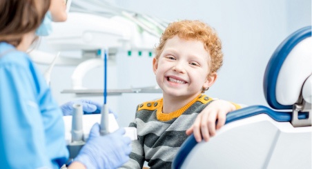A little boy smiling in a dentist beside his female dentist