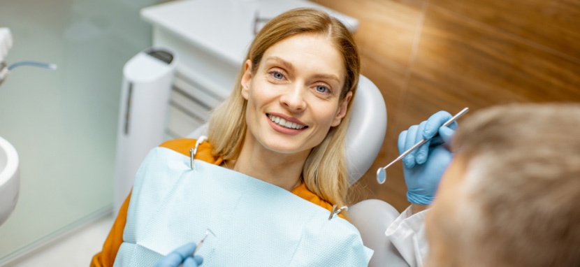 A Lady Smiling in a Dentist Chair Beside with her Dentist
