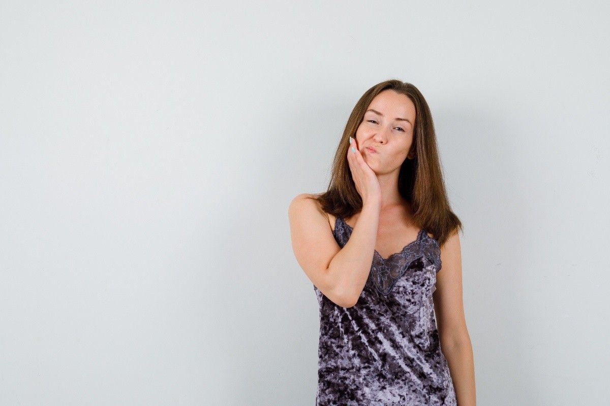 Woman holding her cheek due to severe tooth pain discomfort